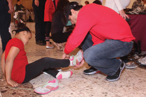 Castillo helps to place shoes on a child of a family living at SAMMinistries Transitional Living and Learning Center.