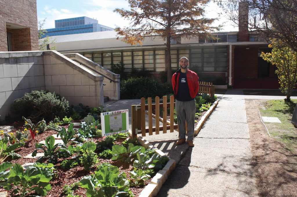 Stephen Lucke poses with the UIW Community Vegetable Garden behind the Gorman Business and Education Center.