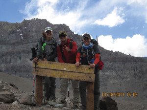 (Pictured L-R) Kim Jordan, a friend who accompanied Magnum; Augustine, a guide from Patagonia; and Mangum at the welcome sign of Base Camp, 14000, where they stayed to acclimate to conditions for three days.