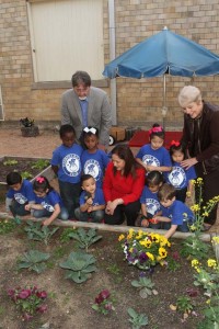 Dr. Jeff Crane (standing, left); Alejandra Barraza (kneeling); and Dr. Mary Ruth Moore (standing, right); share a  moment with students in  Carroll’s vegetable garden. 