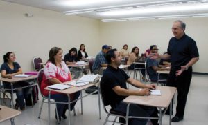 Dr. John De La Garza, adjunct professor of human resource management and organizational development, speaks with students during a SPS class. 