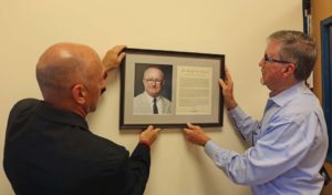 (L-R) Scott LeBlanc, director of sports and wellness, and Carleton hang the official plaque honoring Henrich at the center. 