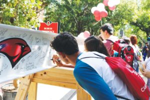 Students sign the beam before it was raised and added to the SEC.