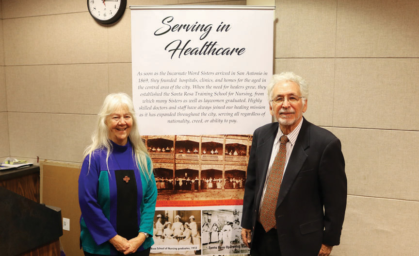 Sr. Martha Ann Kirk, CCVI, and Dr. Gilberto Hinojosa present one of the photo panels from a traveling exhibit of CCVI history.