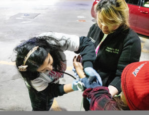 Two members of the PIT Count team take a person's blood pressure.